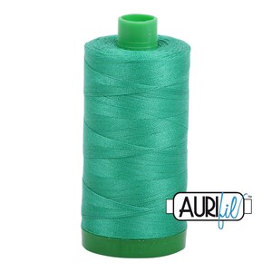 May include: A spool of teal green thread with a green plastic top and a white label that says "AURIfil" in blue.