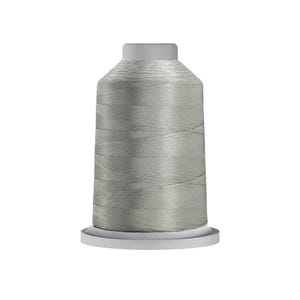 May include: A spool of light gray sewing thread featuring a cylindrical shape with a flat top and a wider circular base. The thread is wound tightly around the central core, displaying a smooth, consistent texture and a subtle sheen throughout.