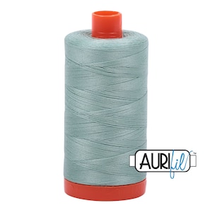 May include: A spool of light blue thread with a red plastic bobbin and the text "Aurifil" on a white background.
