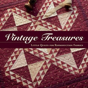 May include: A book titled Vintage Treasures: Little Quilts for Reproduction Fabrics by Pam Buda, featuring a burgundy and cream patchwork quilt with intricate stitching, two wooden thread spools, and a roll of cream lace trim on top.