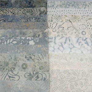 May include: A collection of fabric strips arranged in two columns, featuring a variety of batik patterns in shades of blue, gray, and white. The strips display diverse motifs including floral designs, geometric shapes, dots, and abstract swirls.