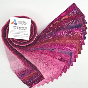 May include: A jelly roll of fabric strips in various shades of pink, magenta, and purple, featuring batik-style patterns. A square white card is attached to the top, displaying the Twisted Threads logo and the text: THANK YOU FOR YOUR ORDER!