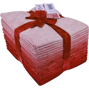 May include: A stack of 40 red and pink ombre batik fabric squares, tied with a red ribbon. The fabric is arranged in a gradient from light pink to dark red. The fabric is packaged with a label that reads "Batik" and "Haywood".