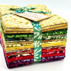 May include: A stack of 20 fabric squares in various shades of yellow, green, orange, red, and purple. The fabric has a batik pattern and is tied together with a green ribbon. The label reads "Java Batik".