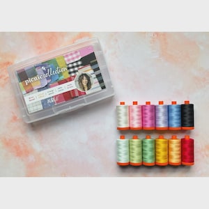 May include: A clear plastic storage box labeled Picnic Collection containing twelve spools of thread, accompanied by twelve individual spools of thread in various colors including white, pink, purple, blue, black, green, yellow, orange, and red.