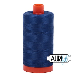 May include: A spool of dark blue sewing thread with a bright orange plastic top and base. The thread is wound tightly around the cylindrical core. The brand name Aurifil is printed in black and blue text on a white rectangular label.