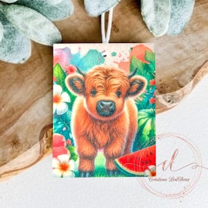 May include: A cute, brown Highland cow calf with a fluffy mane stands in a tropical garden setting. The calf is surrounded by lush green foliage, pink flowers, and a slice of watermelon.