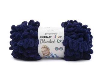 Puede incluir: Una madeja de hilo azul marino oscuro Bernat Alize Blanket-EZ con bucles preformados para tejer con los dedos. La etiqueta central de papel blanco muestra la marca, el título del producto, la foto de una persona y un peso de 180 g.