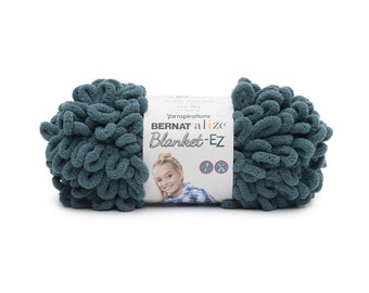 Puede incluir: Un ovillo de lana Bernat Alize Blanket-EZ color verde azulado oscuro con bucles preformados para tejer con los dedos. La etiqueta de papel blanco muestra la marca, el nombre del producto y una imagen de una persona con una prenda estampada.