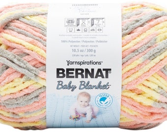 Puede incluir: Una madeja de hilo Bernat Baby Blanket en un patrón de rayas multicolores de rosa, amarillo y gris. El hilo es 100% poliéster y pesa 300 gramos (10,5 onzas). La etiqueta dice "Yarnspirations Bernat Baby Blanket".