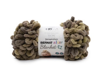 Puede incluir: Un ovillo de lana Bernat Alize Blanket-EZ en tonos marrones y verdes. El hilo pesa 180 g y está hecho de 100% poliéster. La etiqueta dice "Yarnspirations" y "Blanket-EZ".