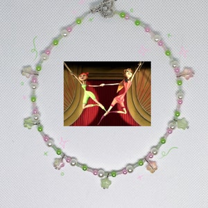 May include: A pink and green beaded necklace with star-shaped charms. The necklace has a silver clasp and is decorated with white pearls.