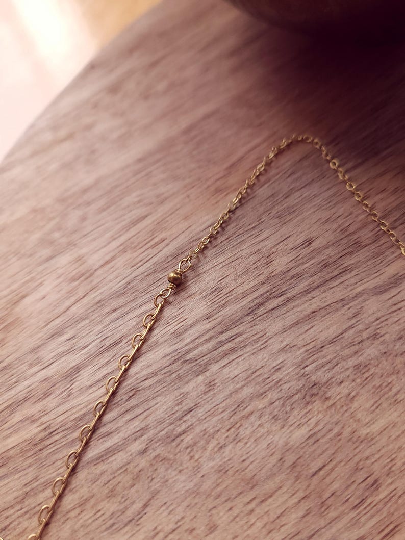 May include: A delicate gold-toned chain necklace featuring a series of small, evenly spaced round metal beads integrated directly into the link structure. The chain consists of thin, interlocking circular links that create a continuous, refined appearance.