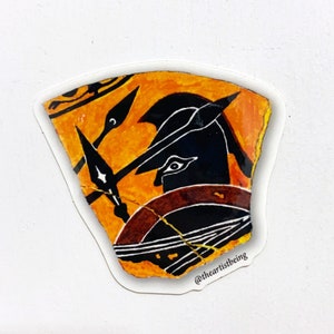 Puede incluir: Un fragmento de cerámica negro y naranja con una imagen pintada de un guerrero con casco y sosteniendo una lanza. El fragmento está agrietado y tiene un borde blanco. El texto "@theartistbeing" está impreso en la esquina inferior derecha.
