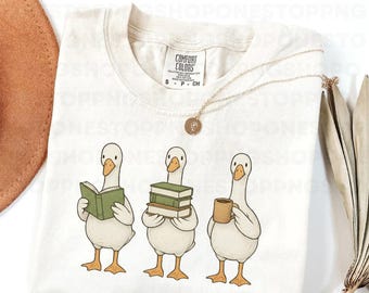 Goose reading books PNG, cute goose clipart, book lover goose illustration, coffee goose design, cozy goose digital art, reading goose PNG