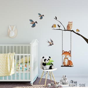 Puede incluir: Una cuna blanca con una manta de estampado amarillo y blanco y una sábana de estampado colorido. Un peluche de panda se sienta en una silla blanca con patas de madera. Una calcomanía de pared presenta un zorro en un columpio, un búho, pájaros y una rama de árbol. El texto "RIGHT SIDE" está impreso en el suelo.