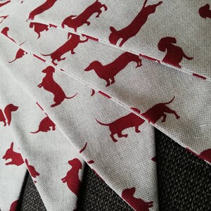 May include: A set of fabric pennants with a white background and red dachshund silhouettes. The pennants are arranged in a fan shape.