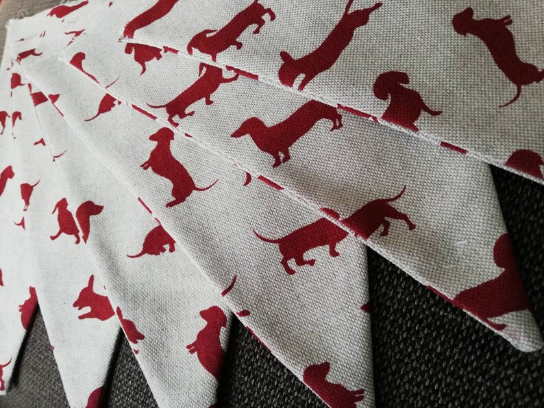 May include: A set of fabric pennants with a white background and red dachshund silhouettes. The pennants are arranged in a fan shape.