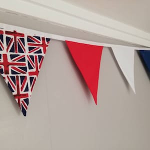 May include: A bunting with red, white and blue triangular flags. The flags are made of fabric and have a Union Jack pattern.