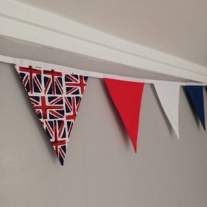 May include: A bunting with red, white and blue triangular flags. The flags are decorated with a Union Jack pattern.