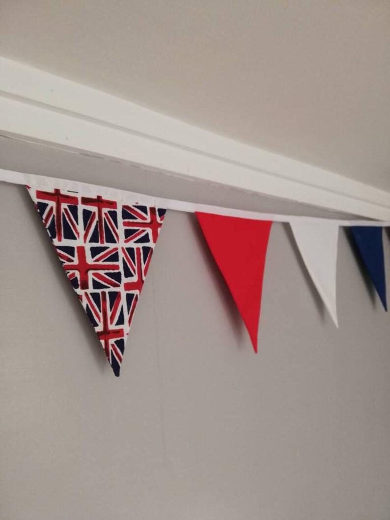 May include: A bunting with red, white and blue triangular flags. The flags are decorated with a Union Jack pattern.