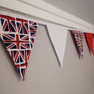 May include: A bunting with alternating red, white and blue triangular flags. The flags with the Union Jack design are red, white and blue. The white flags are plain white.