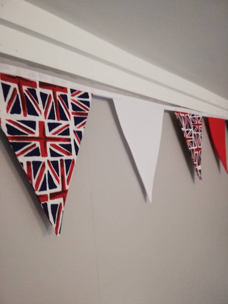 May include: A bunting with alternating red, white and blue triangular flags. The flags with the Union Jack design are red, white and blue. The white flags are plain white.
