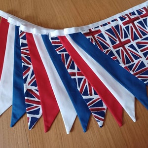 May include: A bunting with alternating red, white and blue triangular flags. The flags feature a Union Jack pattern.