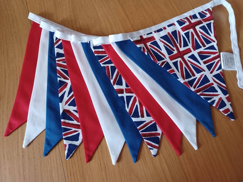 May include: A bunting with alternating red, white and blue triangular flags. The flags feature a Union Jack pattern.