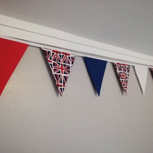 May include: A bunting with red, blue and white triangular flags. The flags have a Union Jack pattern.