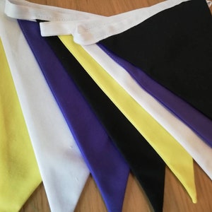May include: A bunting banner with yellow, white, black, and purple triangular flags. The flags are sewn together with white fabric.