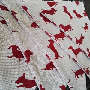 May include: A set of fabric pennants with a repeating pattern of red dachshund silhouettes on a light gray background.
