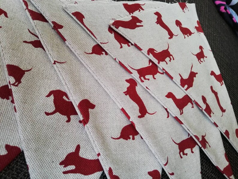 May include: A set of fabric pennants with a repeating pattern of red dachshund silhouettes on a light gray background.