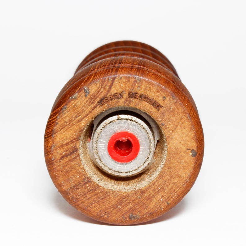 May include: Close-up of a wooden salt and pepper grinder with a red rubber insert and the text "Made in Denmark" on the bottom.