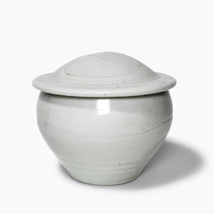 May include: A white ceramic jar with a lid. The jar has a rounded body and a slightly flared rim. The lid has a raised centre and a flat edge.