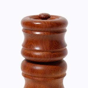May include: A wooden salt and pepper shaker set with a rounded, cylindrical shape. The shakers are made of dark brown wood with a smooth, polished finish.