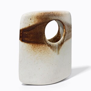 May include: A white ceramic vase with a large circular opening. The vase has a rectangular shape with rounded edges. A band of brown glaze encircles the vase, creating a striking contrast. The vase is approximately 20 cm tall.