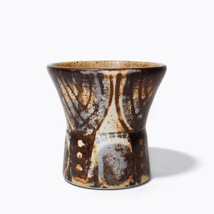 May include: A brown and white ceramic vase with a flared top and a wide base. The vase features a unique abstract design in brown, white and blue.