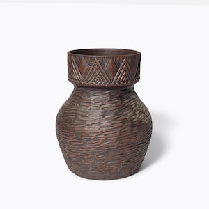 Peut inclure: Un vase en céramique brun foncé avec une surface texturée et un motif géométrique autour du haut.