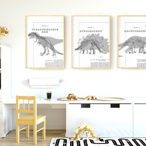 May include: Four framed dinosaur prints with scientific illustrations, including a Tyrannosaurus Rex, Stegosaurus, Brontosaurus, and Triceratops. A wooden dinosaur skeleton and a toy train set are also visible.