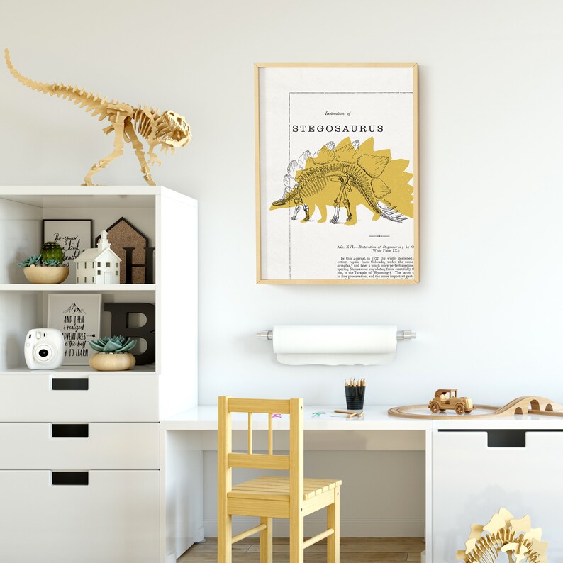 May include: A framed illustration of a Stegosaurus skeleton in yellow on a white background. The text "Illustration of Stegosaurus" is at the top of the frame. The illustration is in a child's room with a wooden dinosaur toy, a shelf with books and plants, and a desk with a chair.