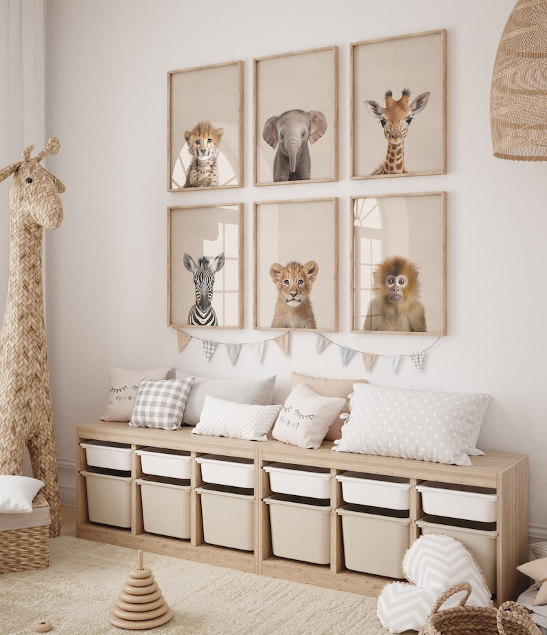 Peut inclure: Une chambre d'enfant avec un banc de rangement en bois avec des bacs de rangement beige et blanc. Le mur est d&eacute;cor&eacute; de six tirages d'animaux encadr&eacute;s d'un gu&eacute;pard, d'un &eacute;l&eacute;phant, d'une girafe, d'un z&egrave;bre, d'un lion et d'un singe. La pi&egrave;ce comprend &eacute;galement un jouet girafe en osier, un jouet d'empilage en bois et un panier en osier.