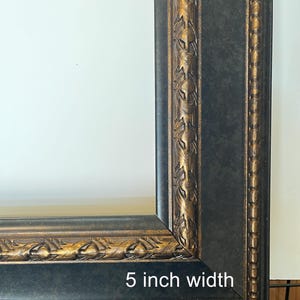 Puede incluir: Primer plano de un marco de fotos negro con detalles dorados. El marco tiene un ancho de 12,7 cm y presenta detalles ornamentados a lo largo de los bordes. El dise&ntilde;o del marco incluye una combinaci&oacute;n de colores negro y dorado, creando un aspecto cl&aacute;sico y elegante.