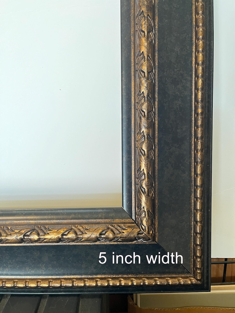 Puede incluir: Primer plano de un marco de fotos negro con detalles dorados. El marco tiene un ancho de 12,7 cm y presenta detalles ornamentados a lo largo de los bordes. El dise&ntilde;o del marco incluye una combinaci&oacute;n de colores negro y dorado, creando un aspecto cl&aacute;sico y elegante.