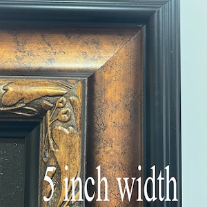 Puede incluir: Primer plano de una esquina de un marco de fotos decorativo. El marco tiene un borde exterior negro y un marco interior texturizado de color bronce con tallas florales ornamentadas. El texto "5 inch width" es visible.