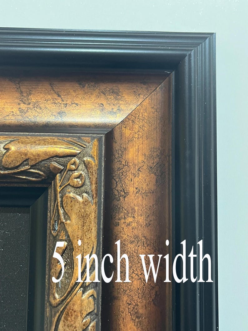 Puede incluir: Primer plano de una esquina de un marco de fotos decorativo. El marco tiene un borde exterior negro y un marco interior texturizado de color bronce con tallas florales ornamentadas. El texto "5 inch width" es visible.