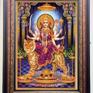 May include: A framed print depicting a multi-armed deity riding a tiger. The deity wears a jeweled crown and purple robes, holding various objects. The tiger is orange and black. The background is blue with ornate architectural details. The frame is brown.