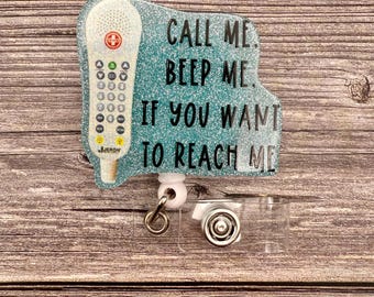 May include: A teal blue glitter badge holder with a white and red medical alert button and the text "CALL ME. BEEP ME. IF YOU WANT TO REACH ME."