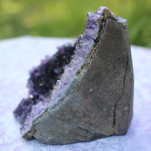 May include: A large amethyst geode with a natural, rough exterior and a purple crystal interior. The geode is a natural formation with a unique shape and texture.