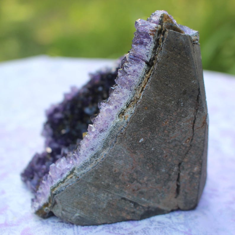 May include: A large amethyst geode with a natural, rough exterior and a purple crystal interior. The geode is a natural formation with a unique shape and texture.
